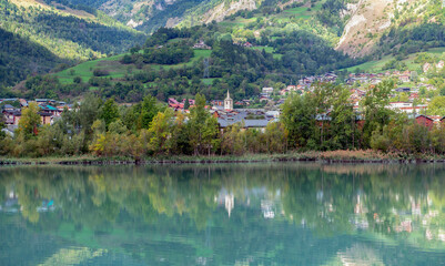 view on alpine french town of Bourg Saint Maurice with reflection on blue water  of  a lake in french alps
