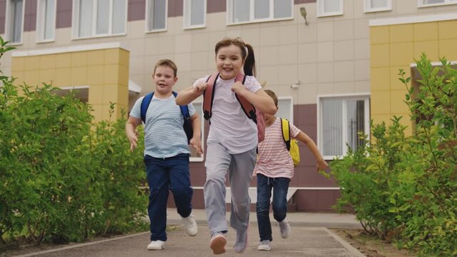 Kids with Backpacks Outside School, Friends Running Together to School, Lively Children at School, Schoolyard Happiness for Kids, Young Learners Coming to School, Cheerful Children at School Entrance