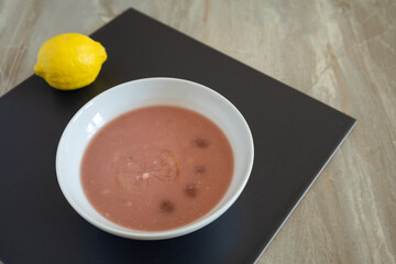 Chilled fruit soup with lemon served in a white bowl