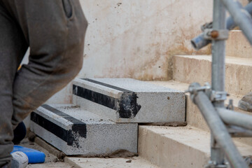 Builders working on construction site to install concrete blocks on stairs to perfect levels according to tolerances
