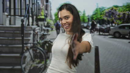 Happy young hispanic woman extends bare hand for warm handshake in busy city street; trust connection.