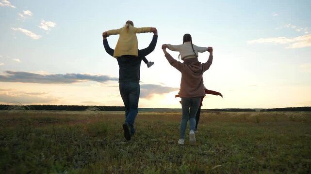 Family time together, Shoulder rides fun, Running in the field, Laughing kids, Parental support, Beautiful dusk, Playful afternoon, Exploring outdoors, Strong family ties, Peaceful memories