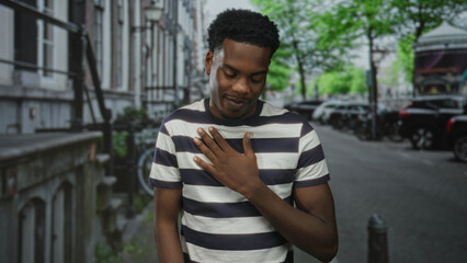 Young african american man clutch chest for heartattack on street with parked cars; pain...