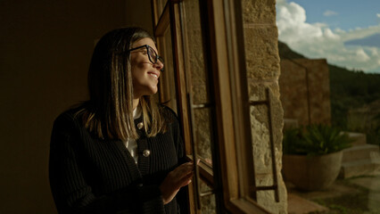 Obraz premium Woman smiling indoors by a window in a mediterranean house during the day.