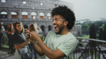 Man with glasses smiling and pointing by the iconic roman coliseum, capturing a lively outdoor...