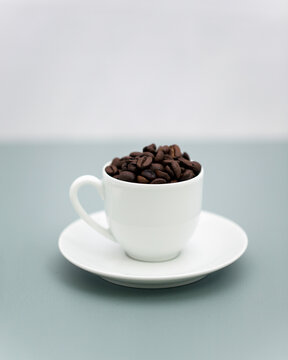 Coffee cup filled with roasted coffee bean on saucer with copy space