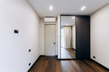 A Stylish Modern Minimalist Bedroom Featuring a Beautiful Mirror and Warm Wooden Flooring