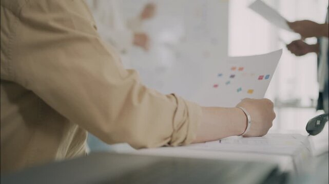 Close up asian senior man professionals reviewing paperwork and charts during a collaborative business planning meeting in a modern office environment.