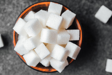 Sugar cubes arranged in a bowl on a dark surface during daytime