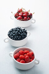 Bowls of raspberries, blueberries and cherries for fruit trio, diet or nutrition concept