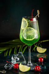 Green cocktail with lime and cherry