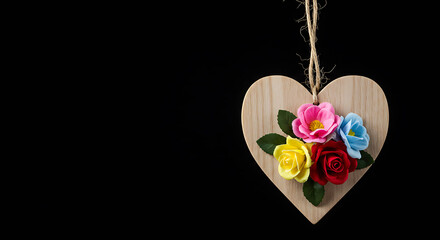 Wooden heart decoration with colorful flowers on black background  