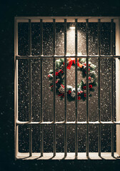 Christmas wreath hanging behind bars with snow falling outside  