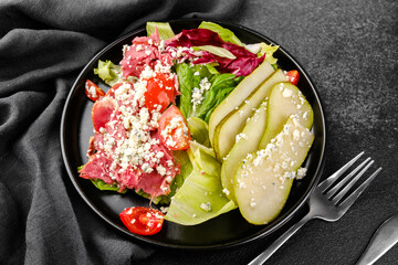Black plate salad with pears and blue cheese for gourmet healthy, restaurant menu or elegant cuisine concept