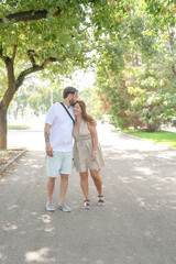 Obraz premium A man and a woman are hugging each other on a street. The man is wearing a white shirt and shorts, and the woman is wearing a dress. They are both smiling and seem to be enjoying each other's company