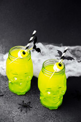 Spooky green drinks in skull jars with marshmallow eyeballs and bat garnishes