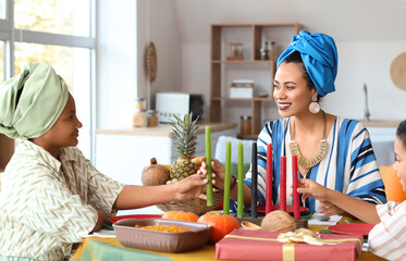 African-American mother with her children and candles having dinner at home. Kwanzaa celebration
