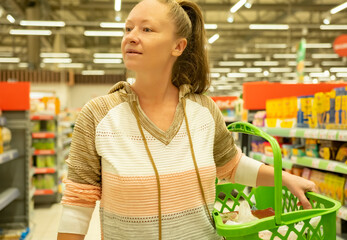 Cheerful woman with shopping basket in supermarket.