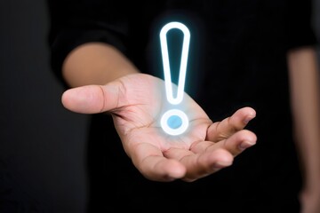 Person holding a glowing exclamation point in their hand against a dark background in a close up shot