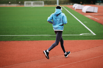Person running with headphones on stadium track