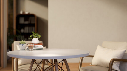 A glass of coffee and books aside potted plants on white round table with chairs in a living room.