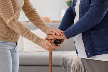 Fototapeta premium Woman and grandmother with stick holding hands at home, closeup. Care concept
