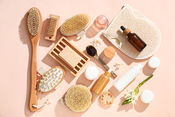 Set of cosmetic products for anti-cellulite massage and flowers on beige background