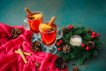 Two cozy glasses of mulled wine with cinnamon sticks and orange slices on a dark backdrop.