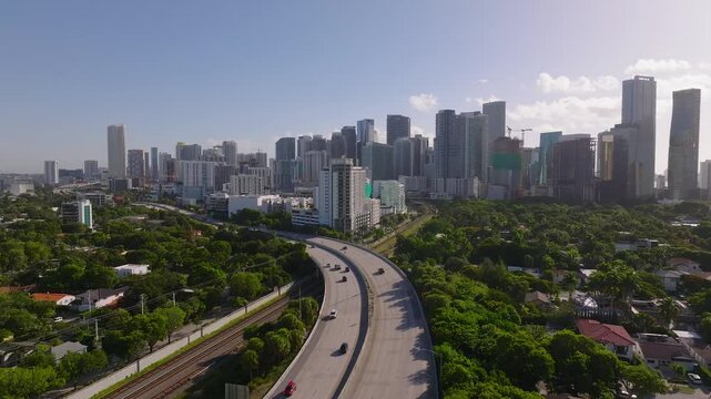 Aerial view of the I-95 highway cutting through lush greenery towards the towering skyline, a blend of nature and urban sprawl, Miami, Florida, United States.