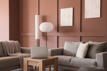 Interior of stylish living room with grey sofas, standard lamps and laptop on coffee table