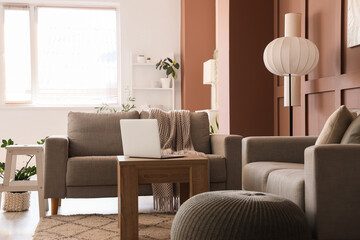 Interior of stylish living room with grey sofas, standard lamps and laptop on coffee table