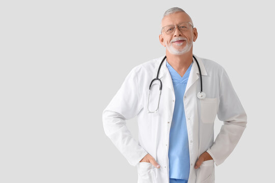 Portrait of senior doctor on grey background - Powered by Adobe