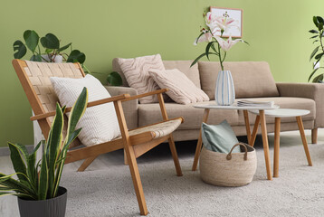 Interior of stylish living room with cozy grey sofa, armchair and coffee table near green wall