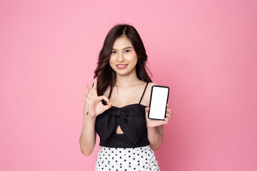 Cheerful smiling Asian woman holding smartphone isolated on pink background.with clipping path