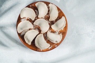 Naklejka premium Homemade dumplings arranged on a wooden plate ready for cooking