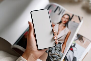 Hand holding phone with white screen near style publication