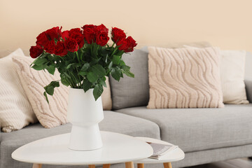 Vase with beautiful red roses on coffee table in stylish living room