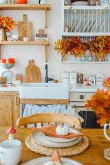 Autumn kitchen decor with orange maple leaves, pumpkins, and rustic wood