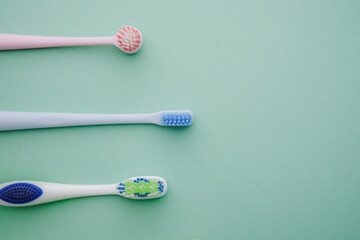 Three colorful toothbrushes lined up on a soft pastel background for dental care.