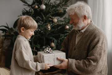 Grandfather giving a gift to his grandson near the Christmas tree. Cozy and joyful holiday moment, warm festive atmosphere.