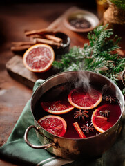 Mulled wine in a small pot on a cozy surface, warm Christmas vibes. Festive holiday beverage scene with aromatic spices.