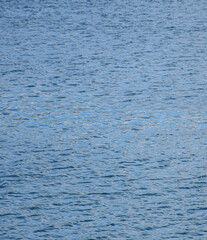 Blue river water texture with soft sky reflections and ripples