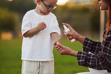 Obraz premium Spray against bugs and flies. Mother and son together in an open field during daytime
