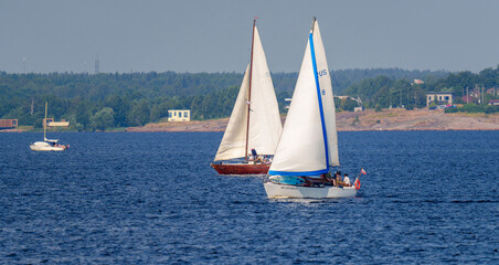 Fototapeta premium Two sailboats on lake near coastal town on a summer day