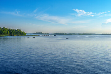 Peaceful lake landscape with rocky shoreline and distant forest