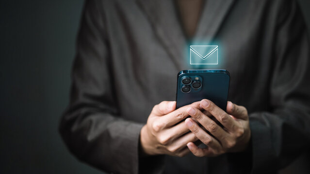 Businessman holding smartphone with glowing email icon for inbox message