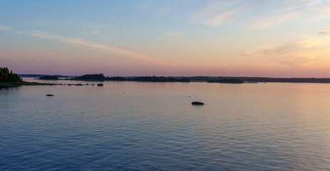 Calm lake with islands and pastel sky at sunset