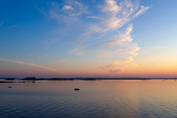 Calm lake with distant forest and pastel sky at sunset