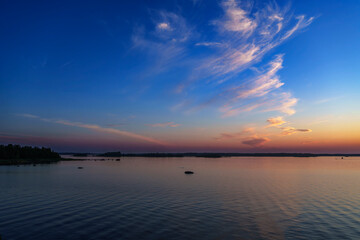 Vibrant sunset over calm lake with dramatic sky and scattered clouds