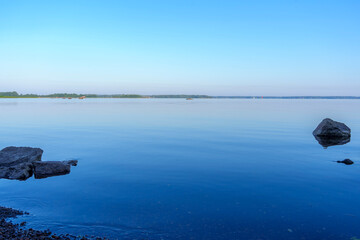 Tranquil lake with rocky shoreline and small islands at dusk
